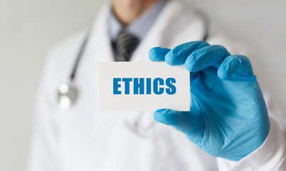 Doctor holding a card with text ETHICS, medical concept