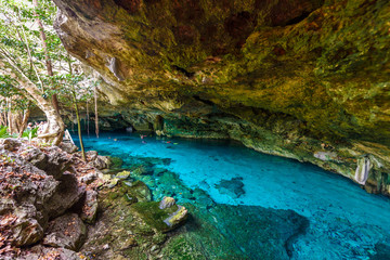 Cenote Dos Ojos in Quintana Roo, Mexico. People swimming and snorkeling in clear blue water. This...