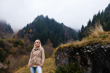 Fototapeta premium Girl travel in mountains alone. Spring weather, calm scene. Backpacker walking outdoors, back view over landscape. Wanderlust photo series.