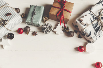 merry christmas concept, flat lay. presents with ornaments pine cones anise on rustic white wooden background top view, space for text. seasonal greetings card. happy holidays.