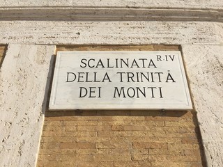 Naklejka premium Rome, Italy - November 8, 2017: Scalinata della Trinità dei Monti (French: La Trinité-des-Monts) street sign on wall. The Spanish Steps lead down to the Piazza di Spagna