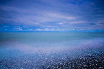 Fototapeta premium Stylized abstract landscape seascape sunset long exposure with clouds under different shades of blue, orange, yellow and red.