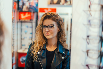 Girl trying on glasses with black rims.
