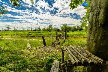 Rural bridge crossing with blue sky, puffy clouds and lush greenery