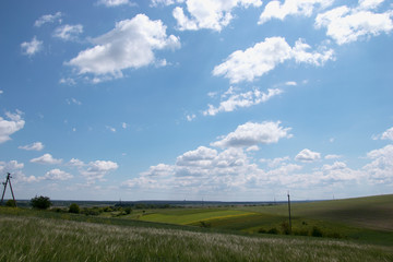 Voluminous white clouds in the blue sky, beautiful summer landscape, fields in the village.