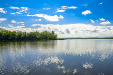 Beautiful rural lake with blue sky and puffy clouds