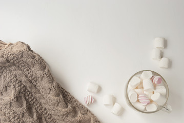 Warm cozy sweater and marshmallow. Winter concept. Flat lay. Top view
