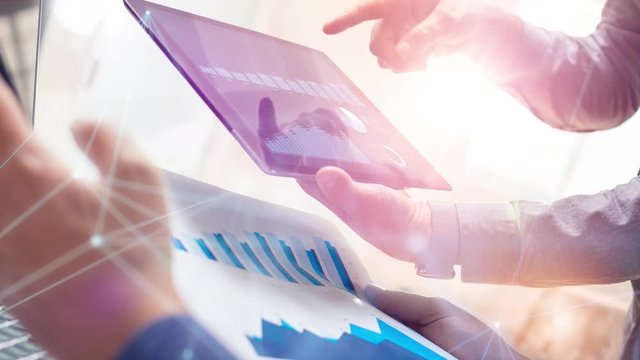 Two colleagues working on global financial strategy using tablet and laptop.Modern business team innovation concept.Office project meeting with virtual graph data interface.4k cinemagraph chart video