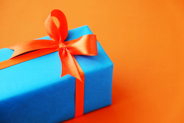 Wrapped present box on orange bright background. Holiday concept. Place for text.