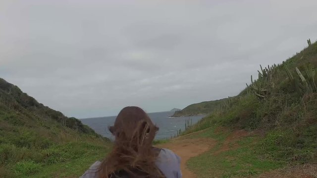 Woman walking in the coast with in a cloudy day with wind