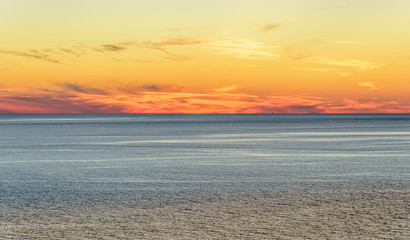 Stylized abstract landscape seascape sunset long exposure with clouds under different shades of blue, orange, yellow and red.