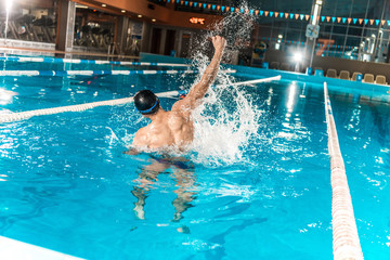 swimmer in pool, winner gesturing and celebrating his achievement, splashes of water
