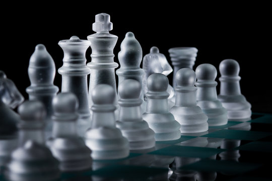 Row of Glass Chess Pieces Standing Ready Before the Start of a Game Against a Black Background