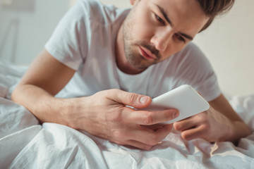 man using smartphone in bed