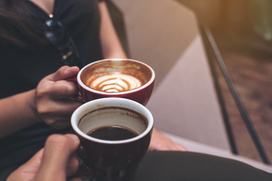 Closeup image of two people clinking coffee cups in modern cafe