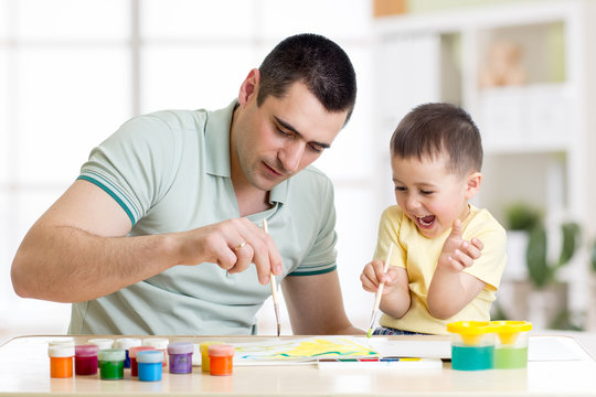 Father and little boy of three years having fun painting at home