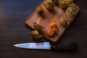 Physalis on a wooden board with a knife.