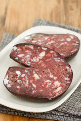 smoked sausage morsela on white dish on wooden background