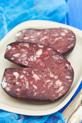 smoked sausage morsela on white dish on wooden background