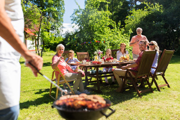 man cooking meat on barbecue grill at summer party