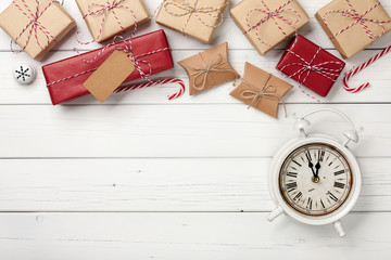 Christmas gift boxes and vintage alarm clock on white wooden background