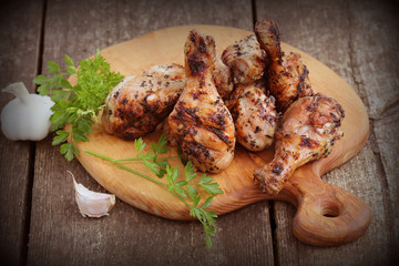 Grilled chicken legs on cutting board.Rustic dinner background