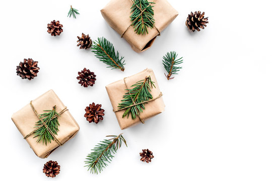 Gifts for new year wrapped in craft paper near spruce branches and cones on white background top view copyspace