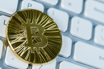 Golden bitcoin at keyboard, macro view background the most popular world crypto-currency. Conceptual image for crypto currency market