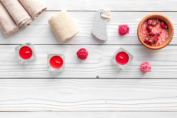 Romantic set for foot spa. Candles, salt, pumice stone, soap on white wooden background top view copyspace