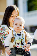 Sweet mother holding her son on her hands posing in the park