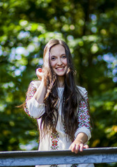 A nice woman wearing an embroidered dress poses in the park