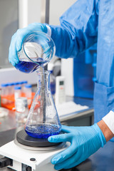 Young male scientist working with an stirrer at laboratory dressed in blue