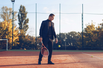 Fototapeta na wymiar Businessman holding tennis racket looking to ball