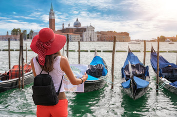 Naklejka premium Elegancka turystka stoi nad Canal Grande w Wenecji i patrzy na swojego przewodnika
