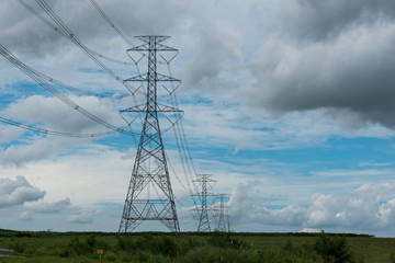 Electricity pylon silhouetted against blue sky wih cloud background. High voltage tower 