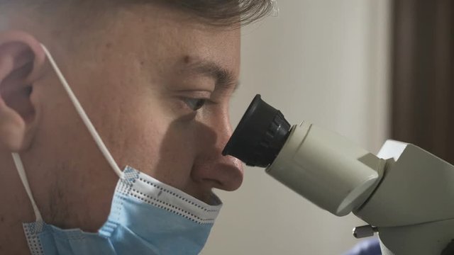 Doctor dentist using dental microscope in modern dental office. Medicine, dentistry and health care concept