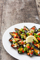 Steamed mussels with peppers and onion on wooden table