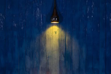 Abwaschbare Fototapete Licht und Schatten Licht eines Scheinwerfers auf einer blauen Holzwand