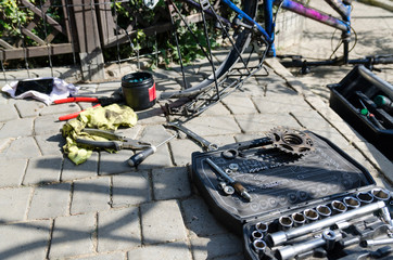 Zepsuty rower, wymiana koła i osi. W tle narzędzia i części.