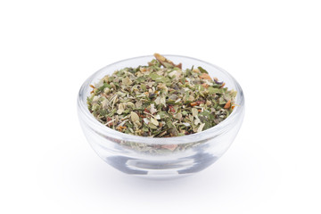 Ground italian herbs in glass bowl isolated on white background