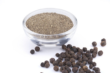 Ground black pepper in glass bowl and peas isolated on white background