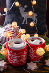 Hot chocolate with marshmallows and biscuits on Christmas decorations background.