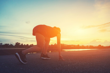 Sports woman prefers for running start pose on the city street. Sport tight clothes. Bright sunset,...