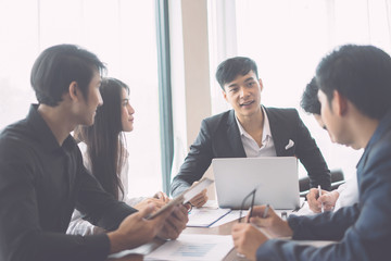 Asian Young man discussing market research with colleagues in a meeting. Business Team of young professionals having a meeting in conference room looking at documents. agreement and hiring concept