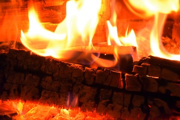 Kaminfeuer mit grell brennendem Holz in rot, gelb und orange