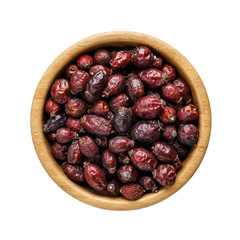 Wooden bowl with dried rose hip berries isolated on white.