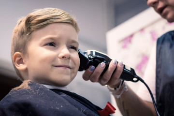 Little boy having haircut at barber shop.