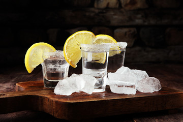 Tequila shot with lime and sea salt on table.