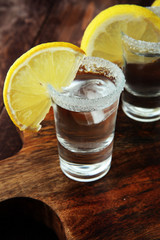 Tequila shot with lime and sea salt on table.