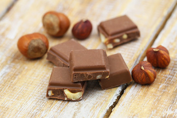 Few pieces of milk chocolates with hazelnuts on rustic wooden surface
